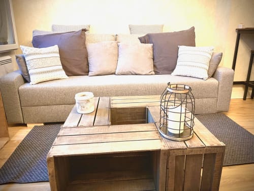 Salon moderne avec canapé beige, coussins décoratifs, table basse en bois et lanterne au Paillot de
