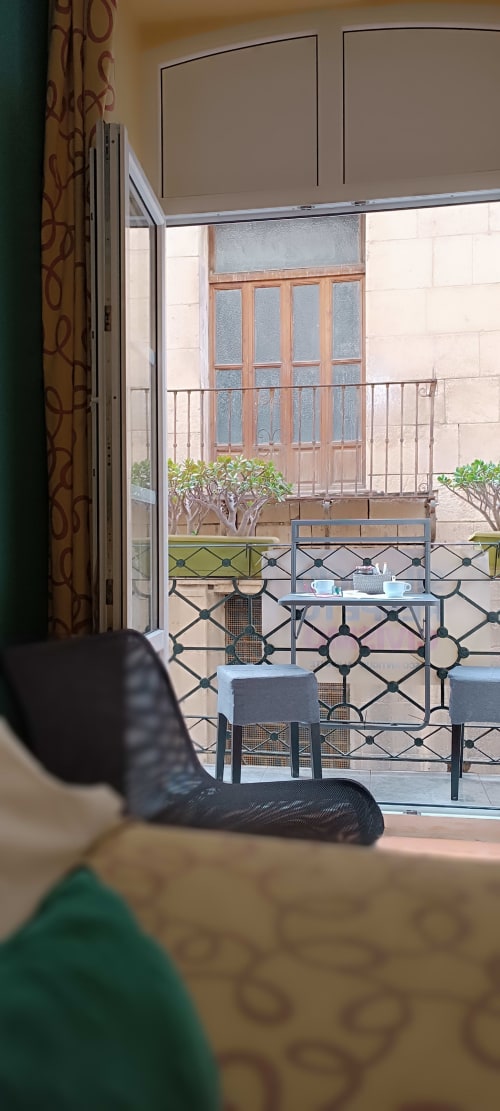 Vista del balcón de la Pensión Alicante San Nicolás con vistas al patio interior de la ciudad, mobiliario y plantas en maceta