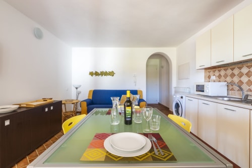 Appartamento Youinsardinia a Bari Sardo con tavolo da pranzo, divano blu e cucina moderna con vista sul giardino