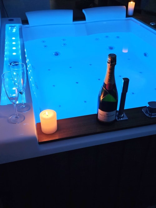 Suite Jacuzzi luxueuse aux Gîtes Saint Valéry-en-Caux avec champagne, bougies et jets d'eau bleus lumineux