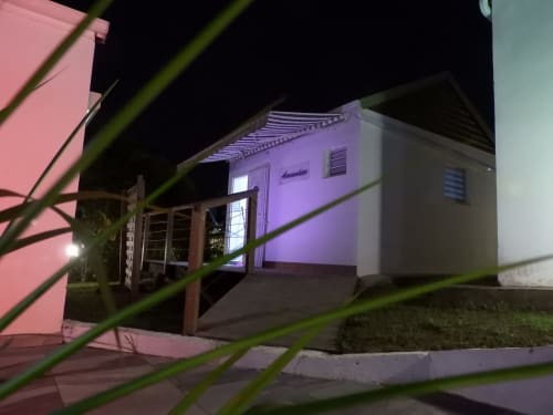 Gîte Kaz A Bibi la nuit à Sainte-Rose, Guadeloupe, illuminé d'une lumière violette et portail d'entrée en bois