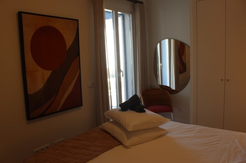 Seaside Fort House bedroom with modern decor, cream bedding, geometric wall art, and curved mirror in Tavira.