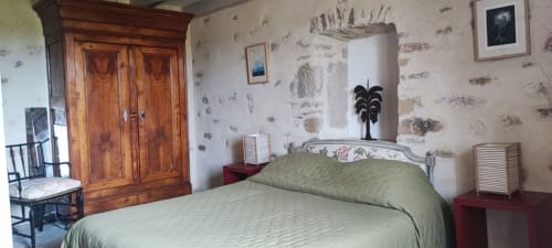 Chambre spacieuse de la Magnanerie de Sainte Croix avec literie verte, armoire en bois et papier peint d'époque à Saint Hippolyte