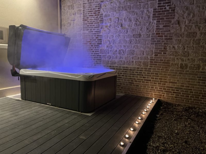 Bain à remous extérieur illuminé aux lumières bleues sur terrasse en bois aux Gites De Flaubert au Héron, France