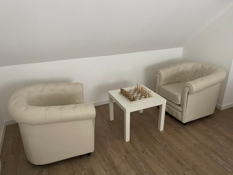 Fauteuils en cuir crème et table de jeu d'échecs dans le salon de la villa Le Bovary aux Gîtes de Flaubert, Le Héron, France