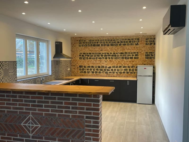 Cuisine moderne aux Gites De Flaubert avec mur en briques, armoires noires, plan de travail en bois et appareils inoxydables