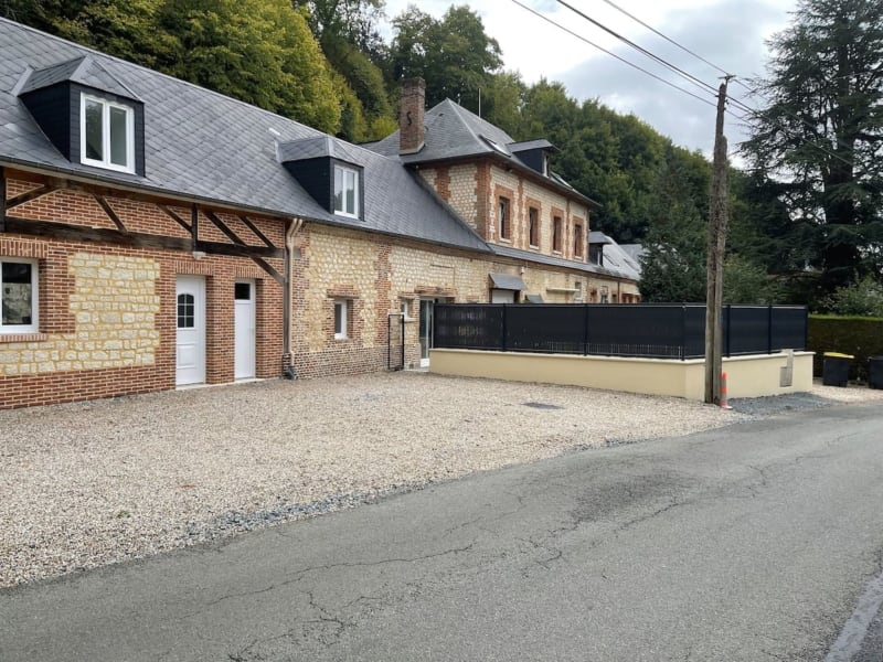 Gîte en pierre et brique aux toits noirs, allée gravillonnée et portail noir à Le Héron, France