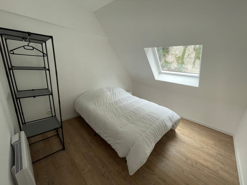 Chambre mansardée minimaliste aux Gîtes de Flaubert : lit blanc, étagères noires, lucarne et parquet