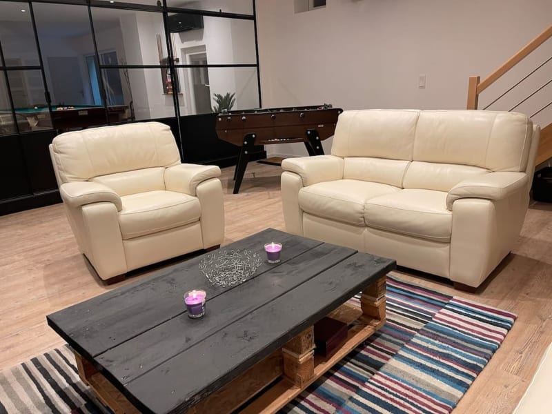 Salon moderne aux Gîtes De Flaubert avec sièges en cuir crème, table basse noire et baby-foot à Le Héron