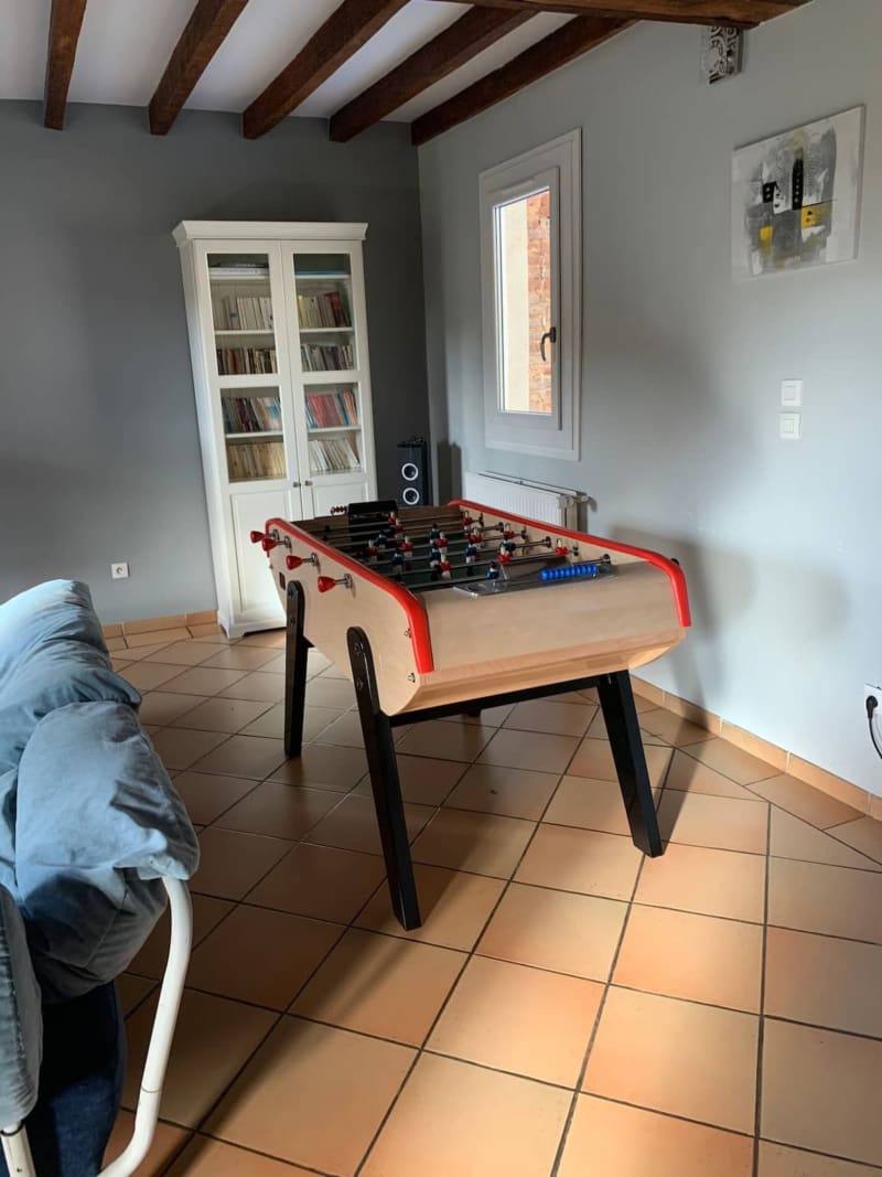 Salle de jeux récréative aux Gîtes De Flaubert avec baby-foot, bibliothèque et canapé