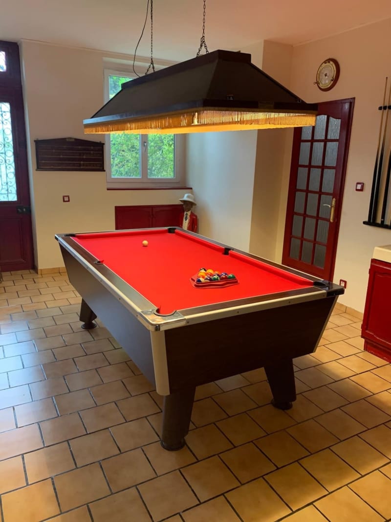 Table de billard rouge avec éclairage suspendu dans la salle de jeux des Gites De Flaubert, Le Heron, France