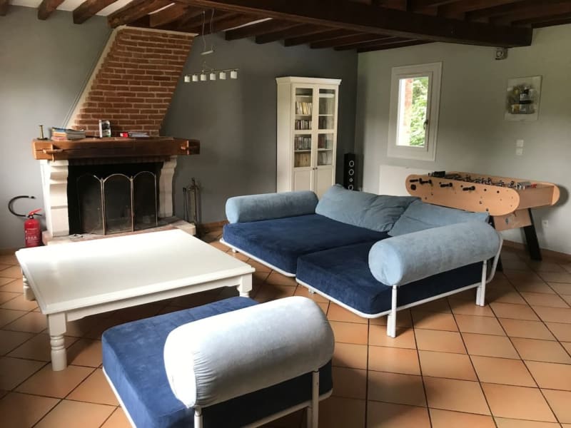 Spacieux salon des Gites De Flaubert avec canapés bleus, baby-foot, cheminée et poutres en bois rustique