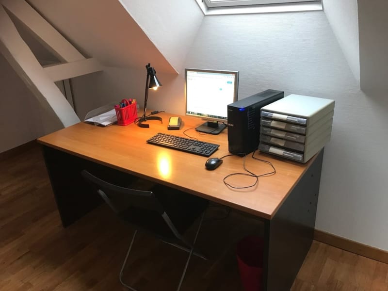 Espace de travail aux Gites De Flaubert avec bureau, ordinateur, clavier et fournitures de bureau sous un plafond mansardé