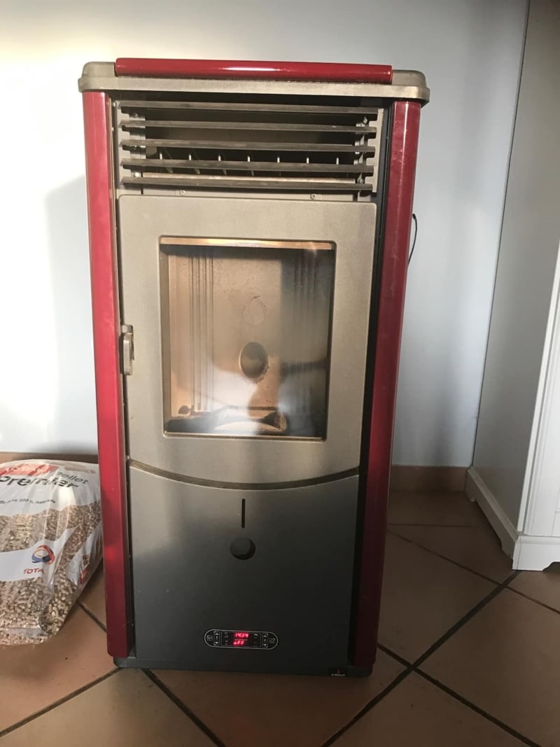 Poêle à granulés rouge et beige du système de chauffage aux Gîtes de Flaubert, hébergement Le Héron