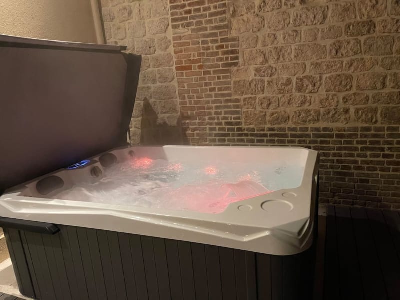 Jacuzzi illuminé d'une lumière rose avec eau bouillonnante à la villa Les Gites De Flaubert au Héron, France