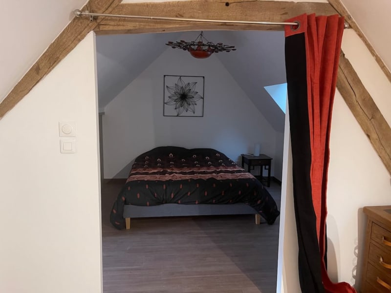 Chambre mansardée aux Gites De Flaubert avec lit, poutres apparentes et rideaux rouges au Heron