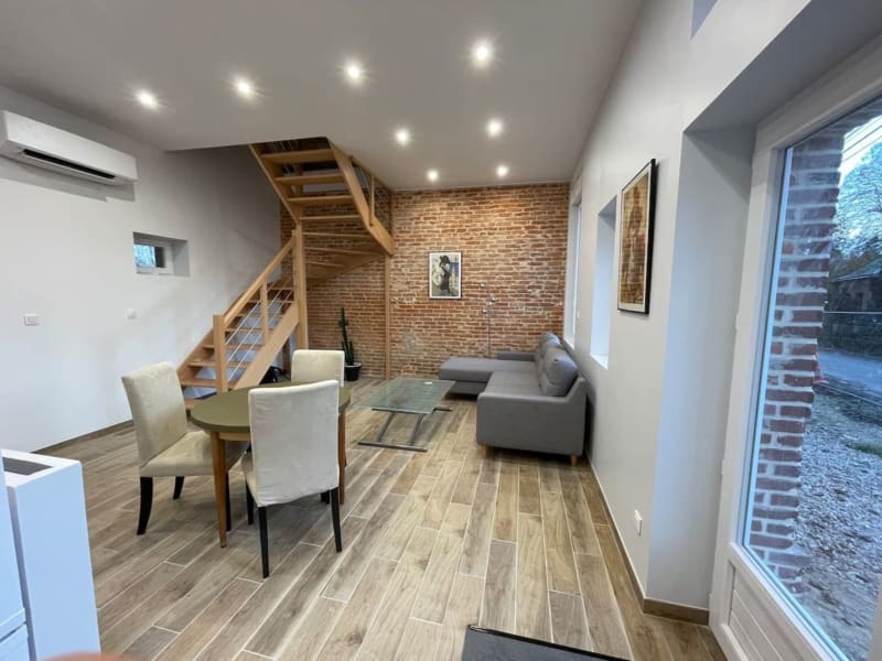 Loft contemporain aux Gîtes de Flaubert avec escalier en bois, mur de briques et coin salon accueillant