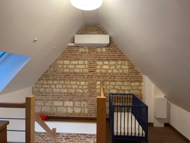 Chambre mansardée aux Gites De Flaubert : murs en brique apparente, lucarne, poutres bois et équipements modernes