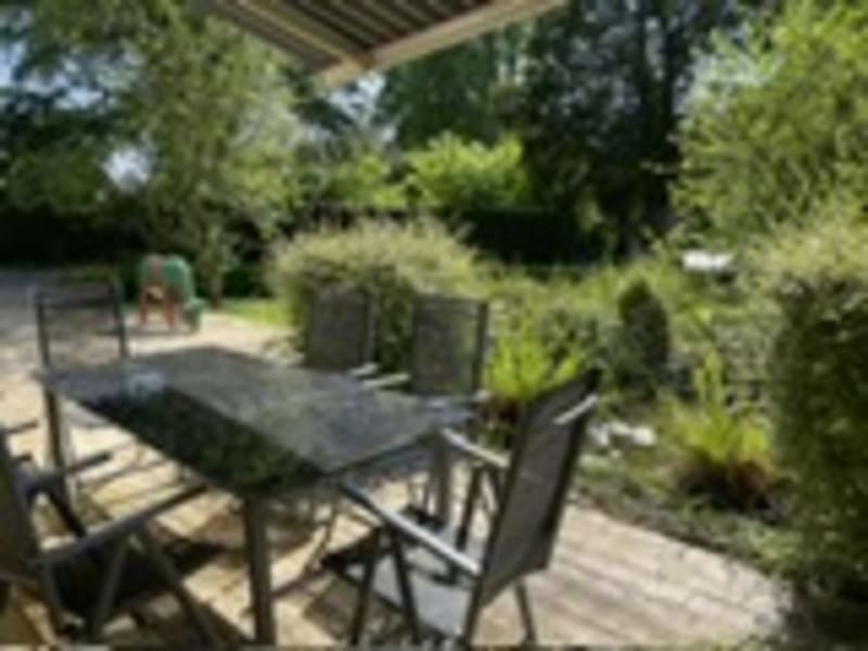 Terrasse de jardin avec salon de détente, table à manger et chaises aux Gîtes de Flaubert au Héron, entourée d'une verdure luxuriante