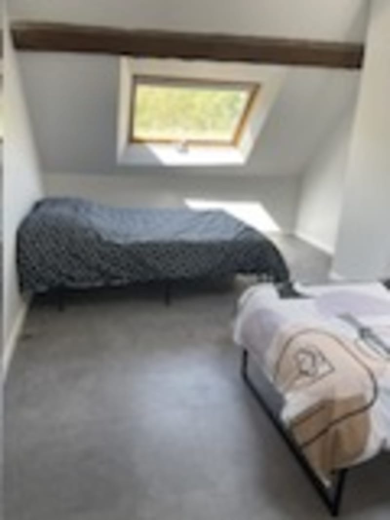 Chambre lumineuse de la villa Les Gites De Flaubert avec lit, fenêtre de toit et vue sur le jardin au Héron