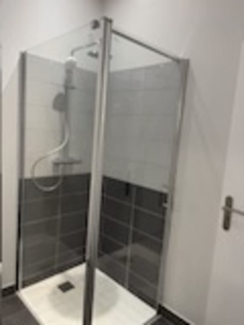 Salle de bain moderne avec douche à portes vitrées et carrelage noir aux Gites De Flaubert, le héron
