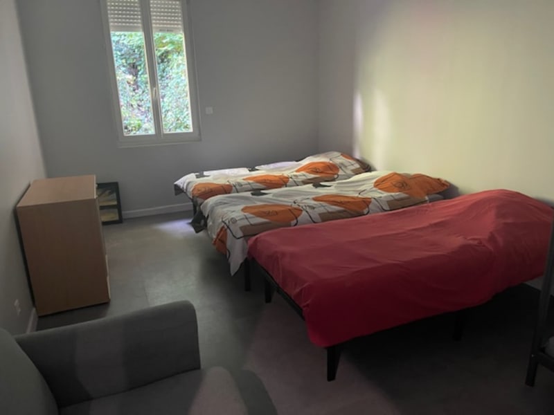 Chambre lumineuse aux Gîtes de Flaubert avec deux lits, literie orange et rouge, fenêtre sur jardin, mobilier épuré