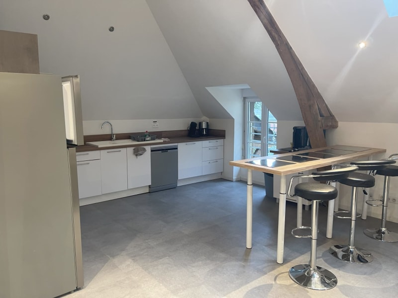 Cuisine mansardée moderne aux Gites De Flaubert avec mobilier blanc, îlot, et plafonds cathédrale
