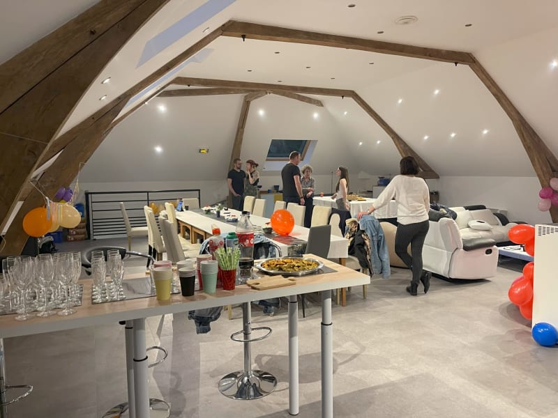 Espace événementiel loft moderne aux Gites De Flaubert avec poutres apparentes, décoration festive et invités qui discutent