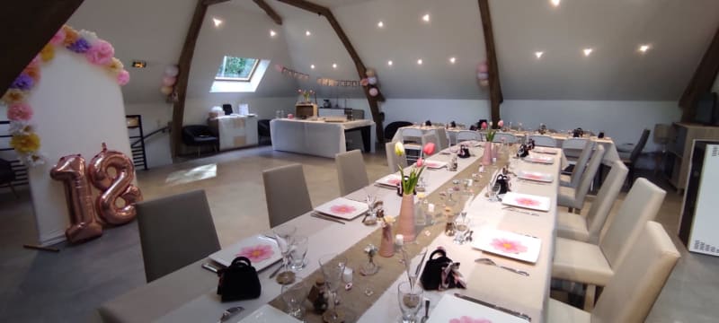 Élégante salle à manger des Gîtes de Flaubert avec longue table blanche, décoration rose et vue sur le jardin par les puits de lumière