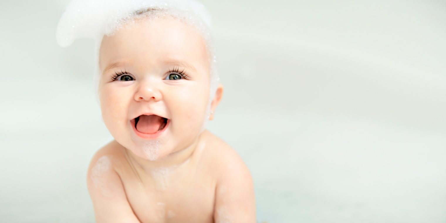 Image of a little baby having fun playing in bathtub soap.