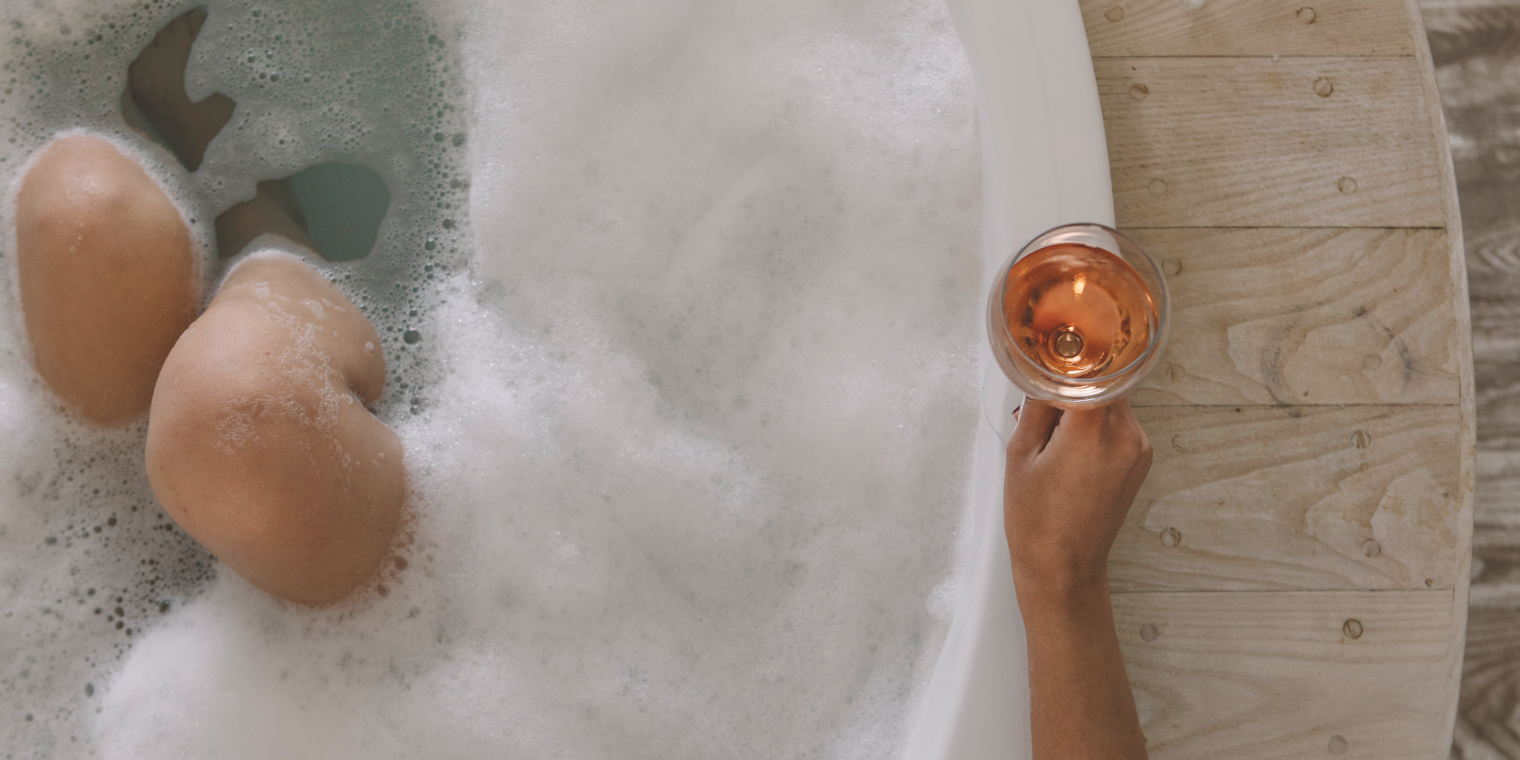 Female enjoy a glass of wine in a bathtub therapy session.