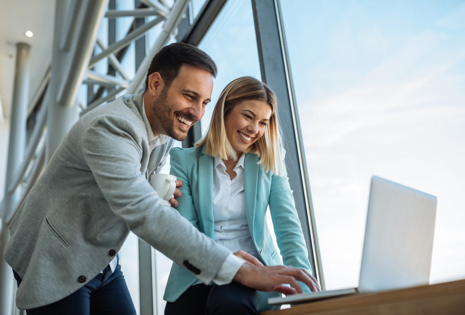 Image of two people who work together feeling happy looking at a lap top.