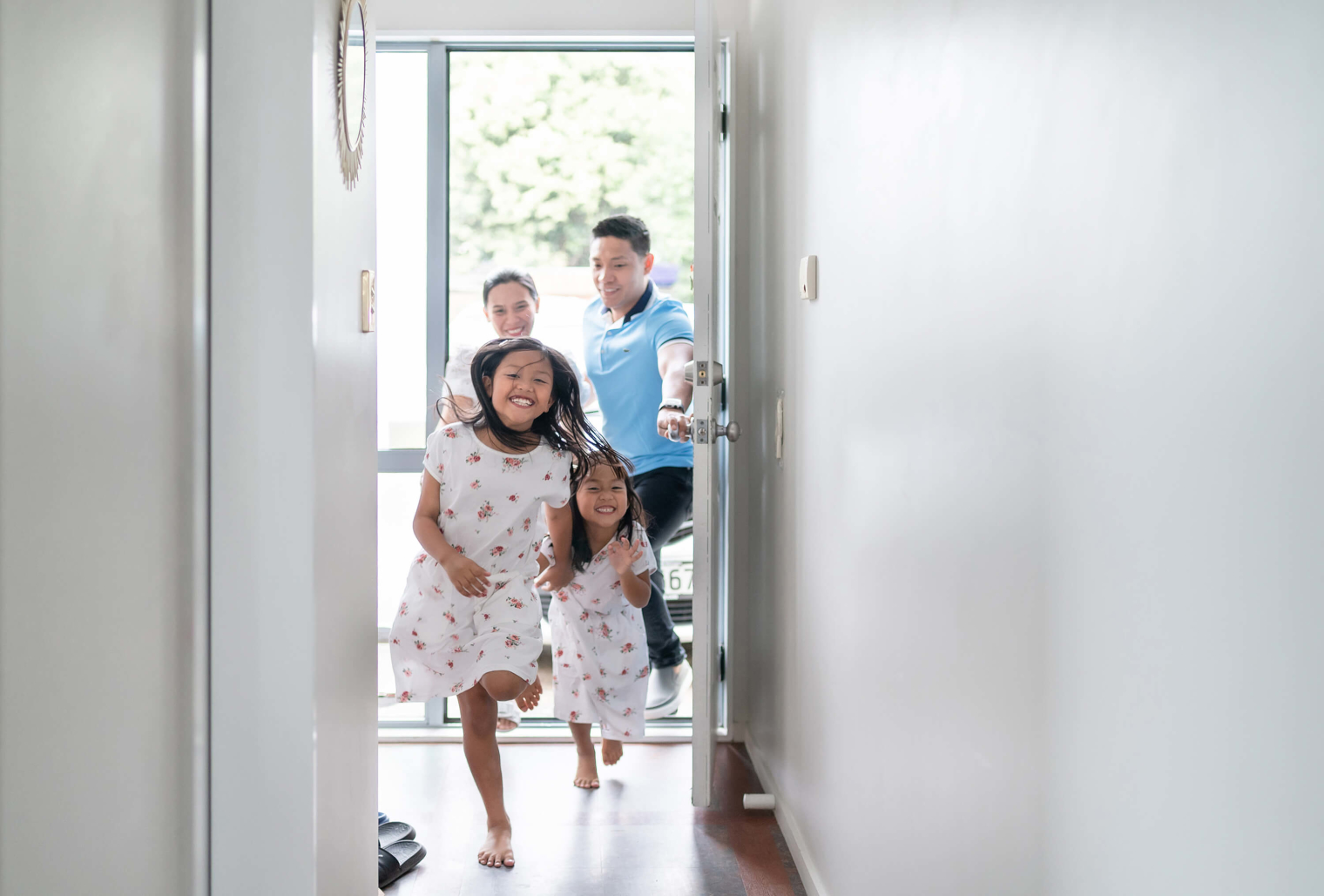 A family of four running inside a house.