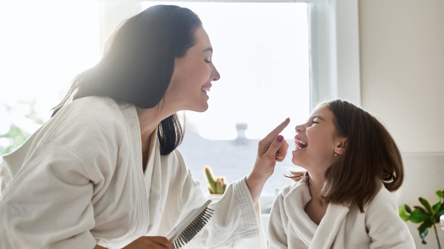 A lady and a child brushing hair in the bathroom