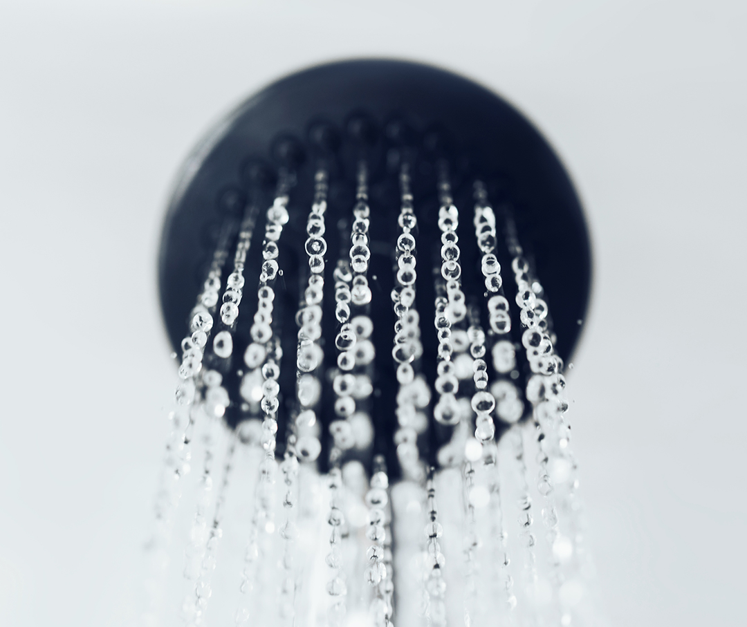 An image of a bronzed shower head with water pouring out.