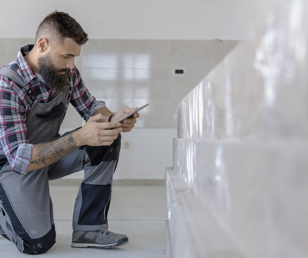 A man kneeling down and using a mobile phone.