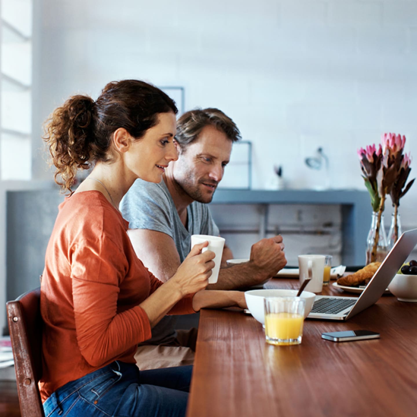 Couple working on laptop at kitchen table.