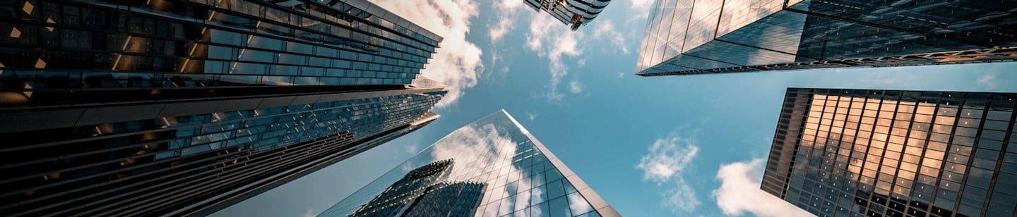 An Image of someone looking up toward the sky that is surrounded by skyscrapers.