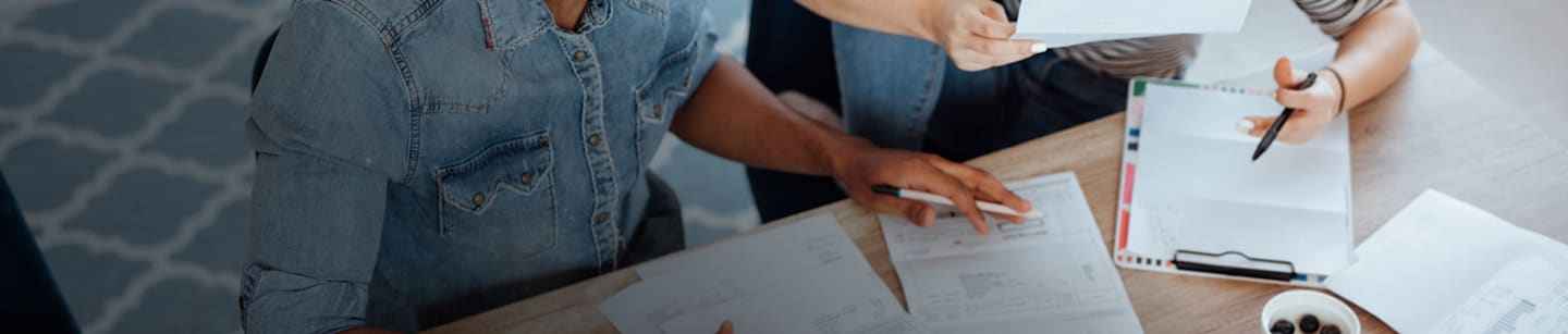 A man and a woman holding pens in their hands while looking over bills.