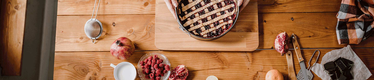 A person placing a freshly baked pie on the table.