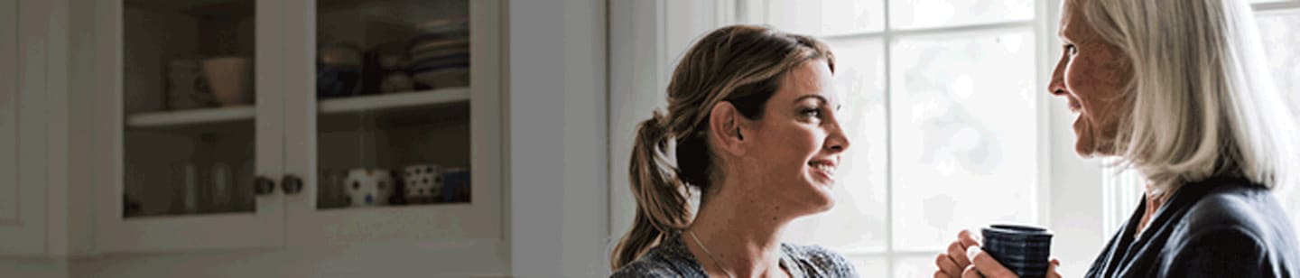 A woman and her mom talking over a cup of coffee.