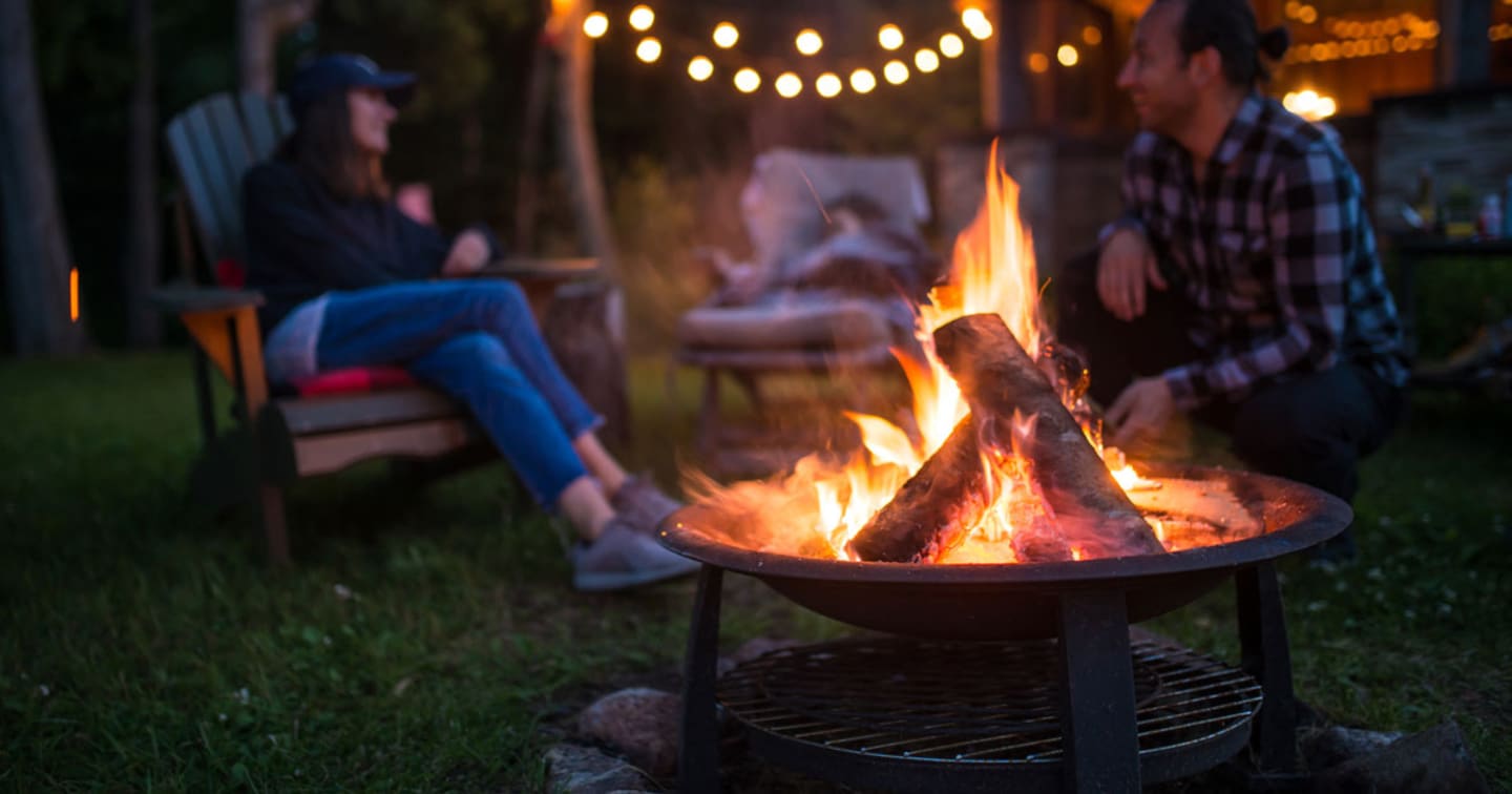 A women sitting beside a firepit.