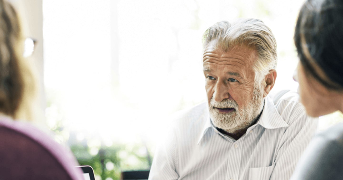 An older gentleman discussing money with his adult kids.