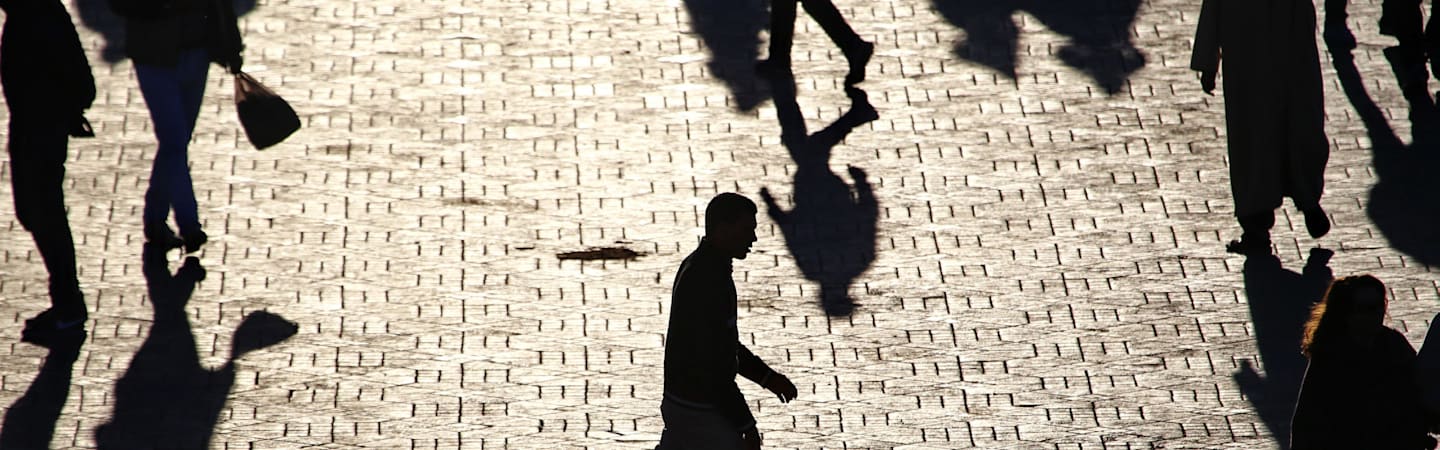 Shadowy figures walking on city street.