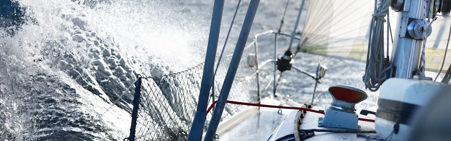 Waves crashing on sailboat in water.