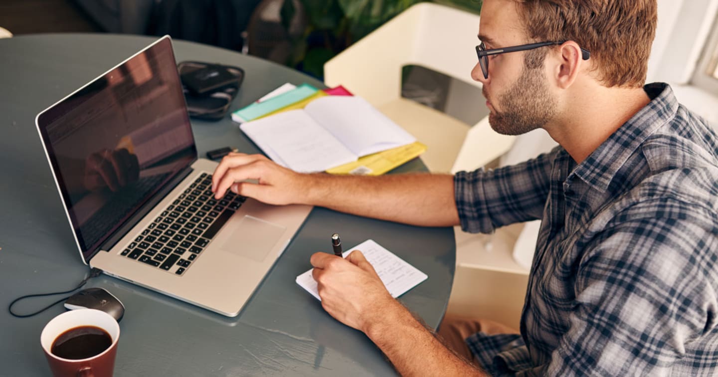 Man working on laptop at kitchen table.