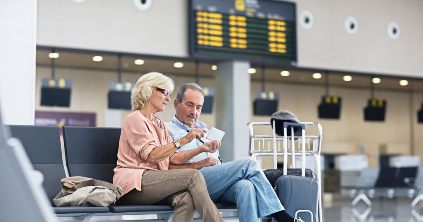 a man and a women sitting next to each other looking at a tablet