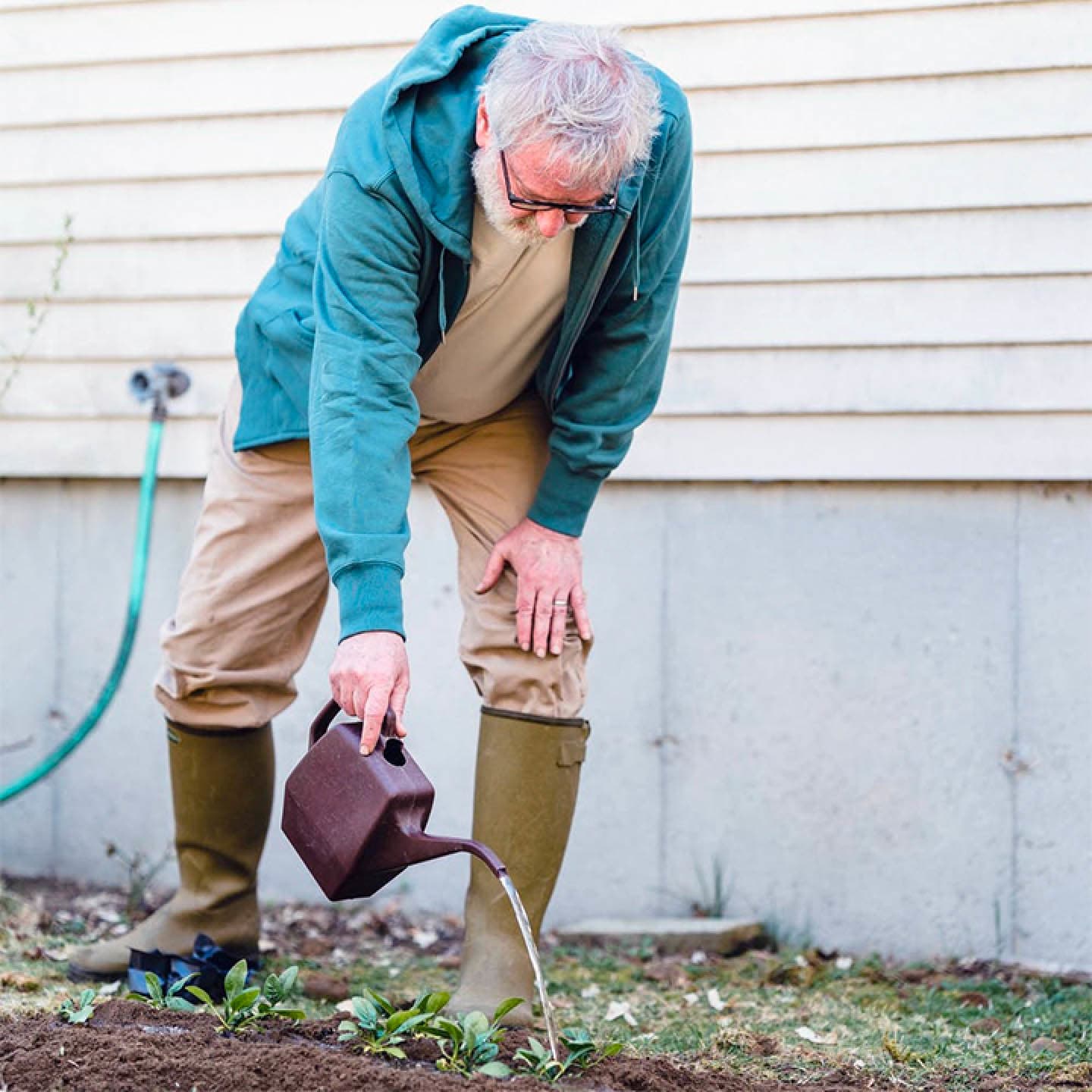 A man outside watering plants