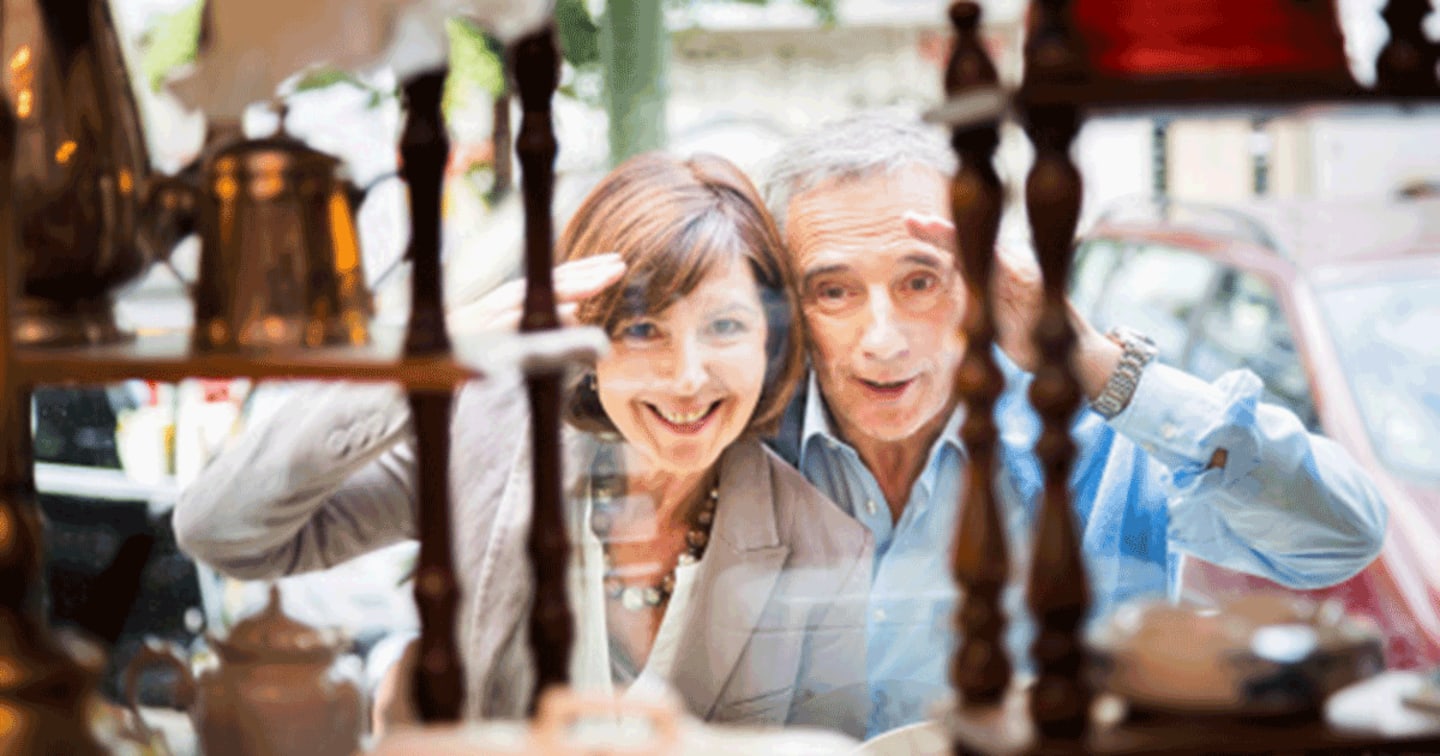 Older couple looking through the window of a antique store.