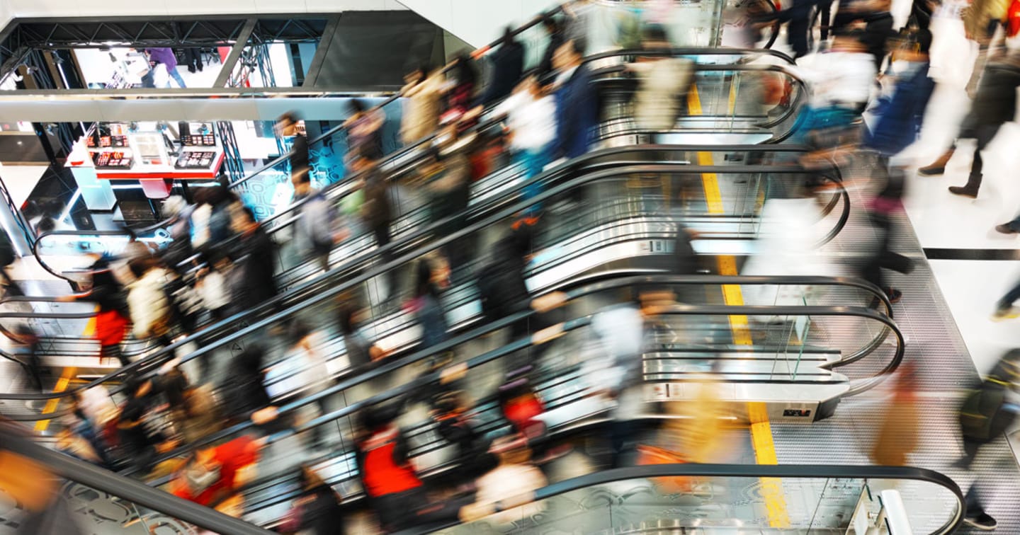 Motion blurred photo of crowd using escalators.